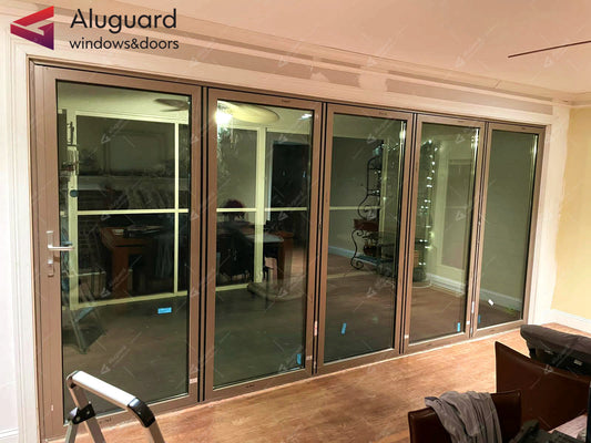 Black aluminum folding glass doors with large panels, creating a modern and open indoor space.