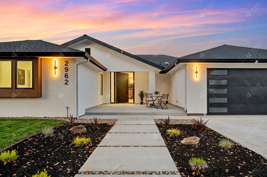 Modern home entrance with a black-framed aluminum entry door at sunset.