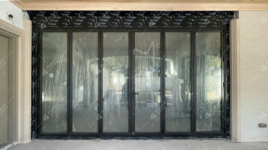 Black aluminum folding door with multiple glass panels installed at a modern residential entrance.